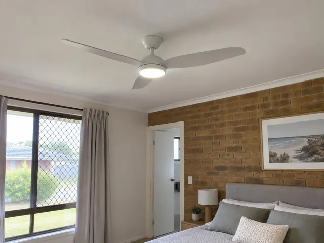 Ceiling fan with light in a bedroom with brick accent wall and window in Wadalba